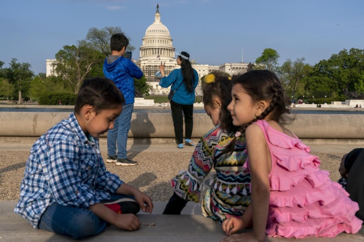 FILE - Members of the Safi family, who were evacuated from Afghanistan and are trying to make a new life in the U.S. while in immigration limbo, celebrate Eid by taking family photographs on the National Mall, May 3, 2022, near the U.S. Capitol in Washington. Growing opposition to the Senate border package once again poses a risk to the more than 76,000 Afghans who worked alongside U.S. soldiers in America&rsquo;s longest war, and who are currently living in the U.S. in immigration uncertainty as a result of years of congressional inaction.