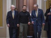 FILE - Ukrainian President Volodymyr Zelenskyy, center, is escorted by Senate Minority Leader Mitch McConnell, R-Ky., left, and Senate Majority Leader Chuck Schumer, D-N.Y., as he comes to the Capitol in Washington to issue a plea for Congress to break its deadlock and approve continued wartime funding for Ukraine, Dec. 12, 2023. Two months later, that aid request had still not been met but Schumer and McConnell are keeping the Senate in session on Super Bowl weekend to force funding for Ukraine and Israel. (AP Photo/J.