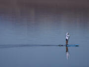 A paddle boarder paddles through water at Badwater Basin, Thursday, Feb. 22, 2024, in Death Valley National Park, Calif. The basin, normally a salt flat, has filled from rain over the past few months.