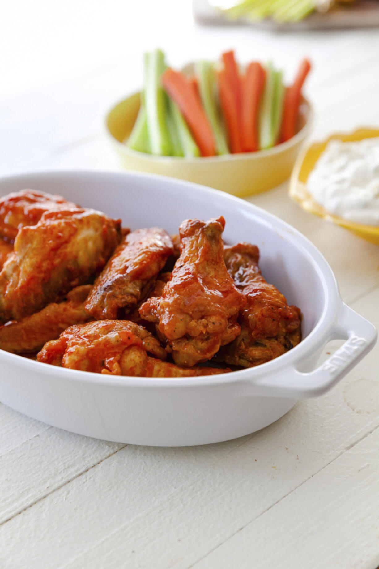 Buffalo chicken wings with blue cheese dip and carrot and celery sticks.