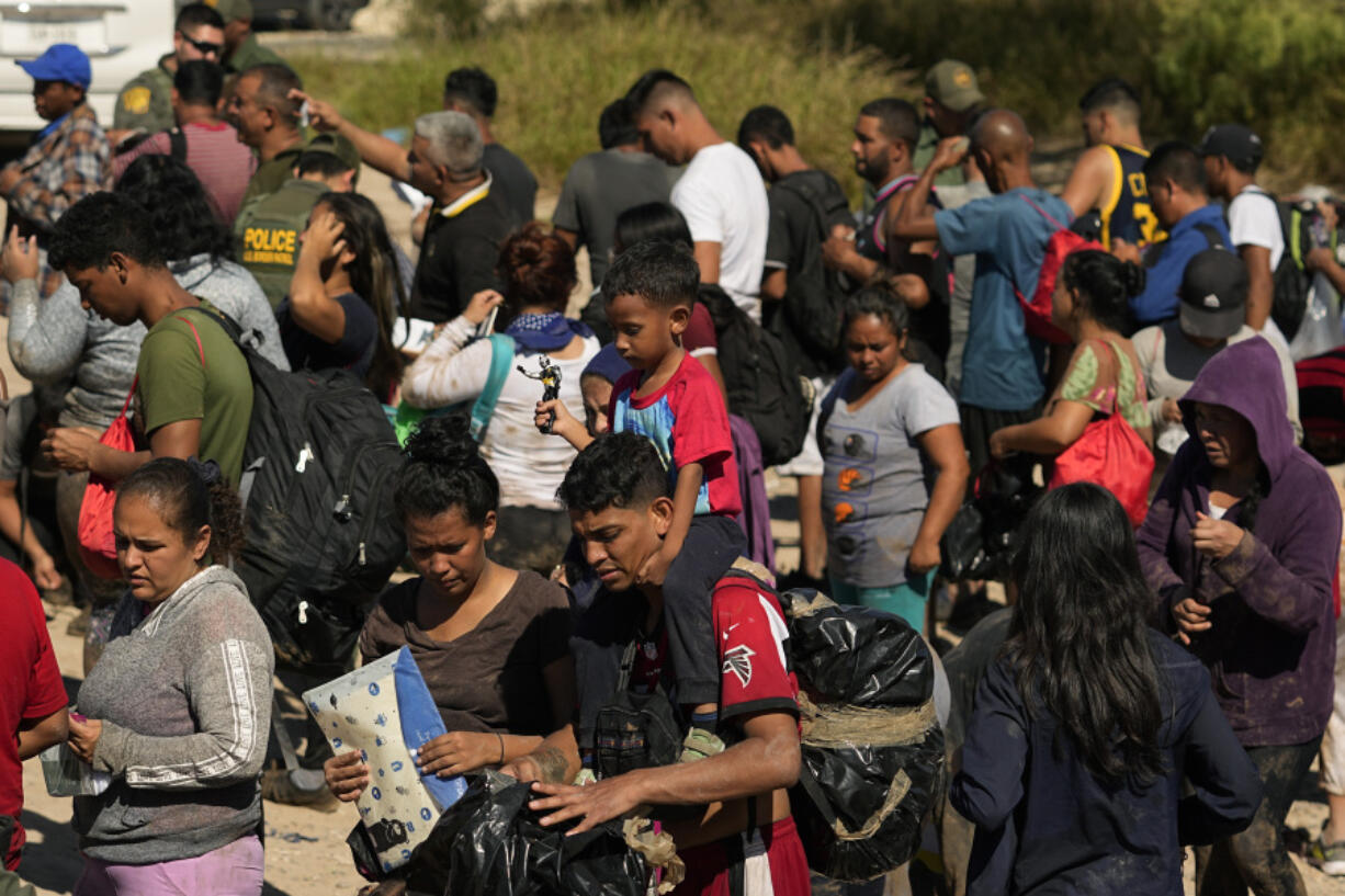 FILE - Migrants wait to be processed by the U.S. Customs and Border Patrol after they crossed the Rio Grande and entered the U.S. from Mexico, Oct. 19, 2023, in Eagle Pass, Texas. A recent decline in arrests for illegal crossings on the U.S. border with Mexico may prove only temporary. The drop in January reflects how numbers ebb and flow, and the reason usually goes beyond any single factor.