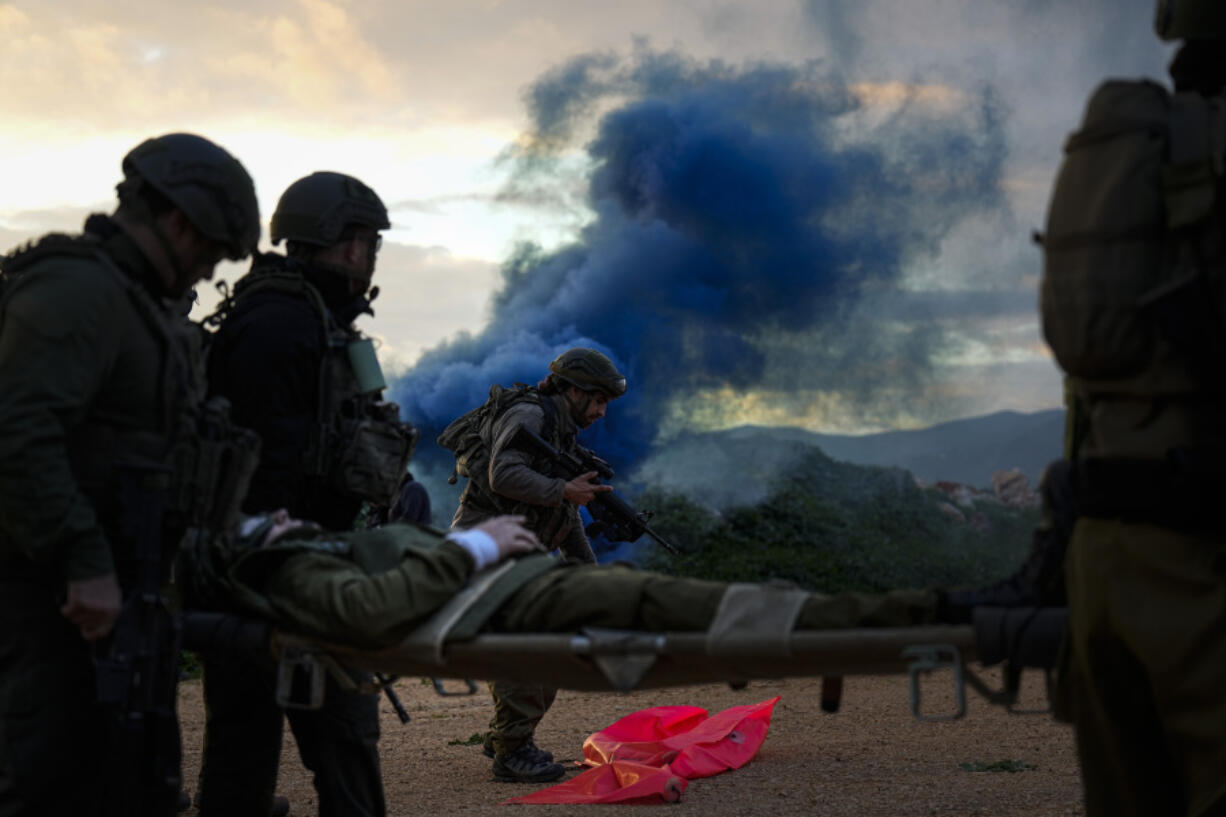 Israeli soldiers run as they carry a stretcher towards a military helicopter during an exercise simulating evacuation of wounded people in northern Israel, near the border with Lebanon, Tuesday, Feb. 20, 2024.