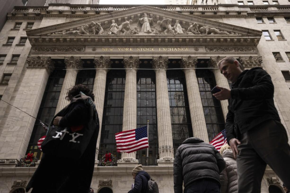 FILE - People walk past the New York Stock Exchange, Dec. 11, 2023, in New York. Just a quarter of business economists and analysts expect the United States to fall into recession in 2024. And any downturn would likely result from an external shock, such as a conflict involving China, rather than from domestic economic factors such as higher interest rates.