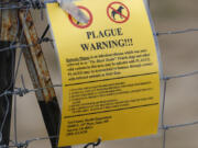 FILE - A bubonic plague warning sign is displayed at a parking lot near the Rocky Mountain Arsenal Wildlife Refuge, Saturday, Aug. 10, 2019, in Commerce City, Colo. Officials in central Oregon this week reported a case of bubonic plague in a resident who likely got the disease from a sick pet cat.