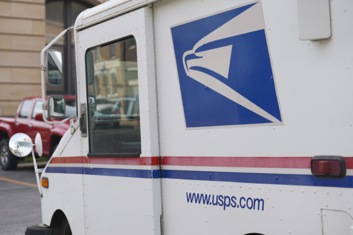 United States Postal Service logo on delivery vehicle outside the post office, Sept. 20, 2023, in Deadwood, S.D. The U.S. Postal Service said announced sweeping plans Tuesday, Feb. 6, 2024 to reduce greenhouse emissions by diverting more parcels from air to ground transportation, boosting the number of electric vehicles, cutting waste sent to landfills and making delivery routes more efficient.