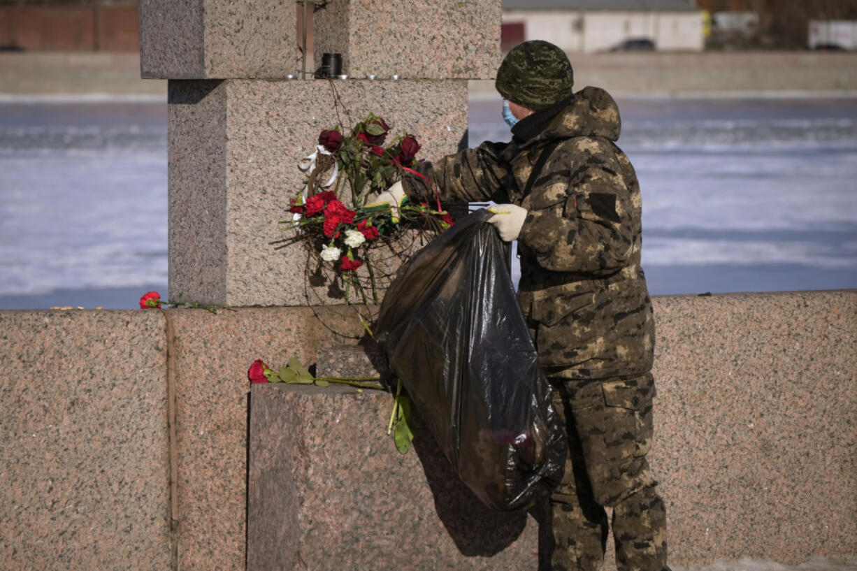 A municipal worker, on orders from the authorities, removes flowers brought by people to pay respect to Alexei Navalny from the Memorial to Victims of Political Repression in St. Petersburg, Russia, Monday, Feb. 19, 2024. Russians across the vast country streamed to ad-hoc memorials with flowers and candles to pay tribute to Alexei Navalny, the most famous Russian opposition leader and the Kremlin&rsquo;s fiercest critic. Russian officials reported that Navalny, 47, died in prison on Friday.