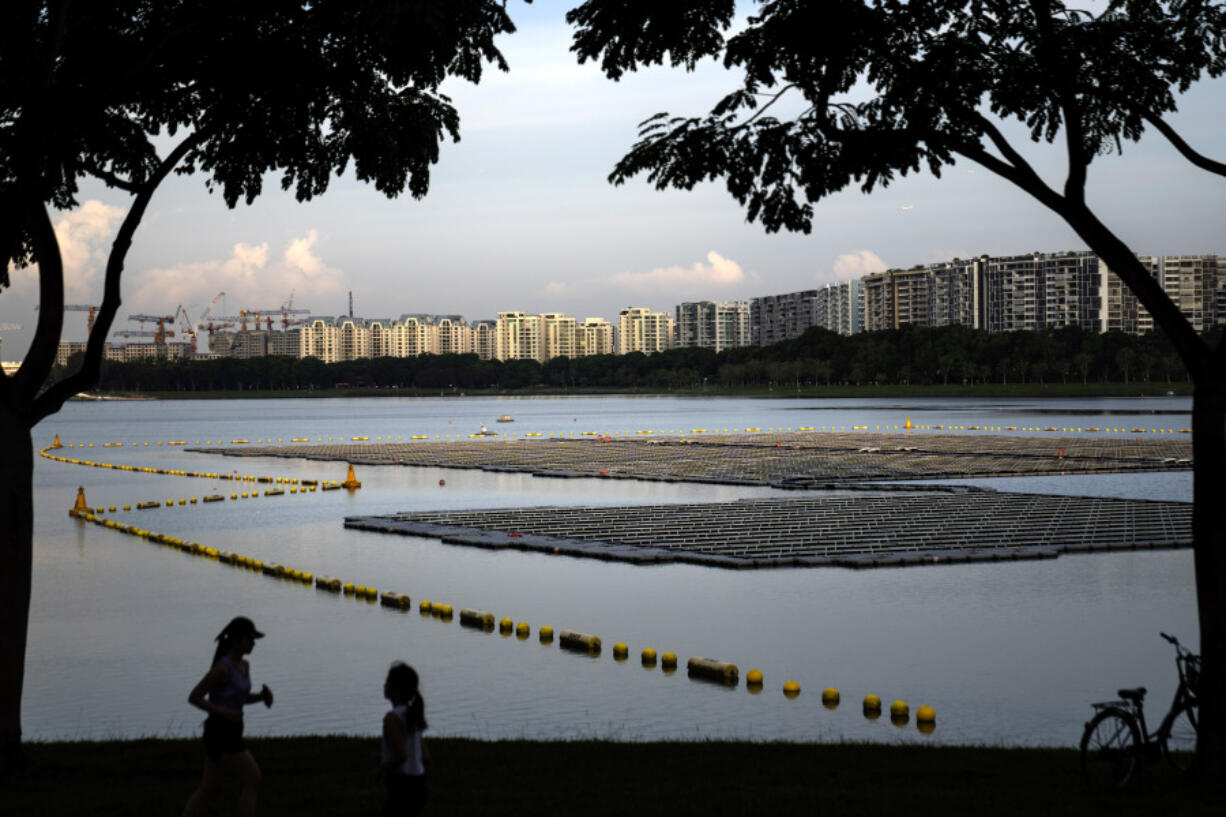 People pass a floating solar panel farm on the Bedok Reservoir in Singapore on July 16.