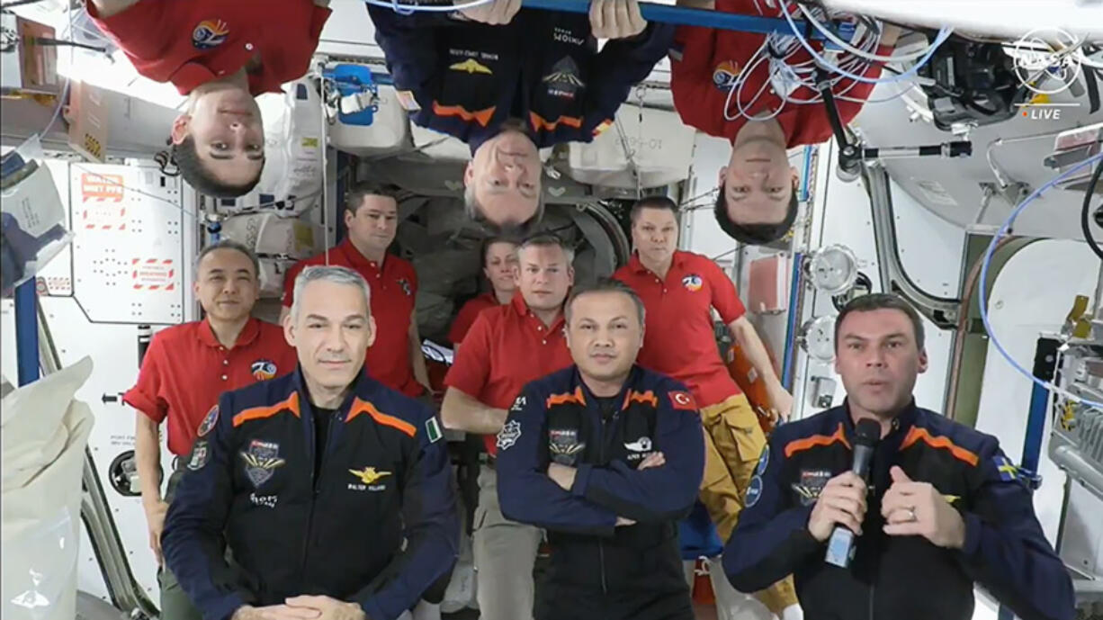 In this image from video provided by NASA, the 11 International Space Station crew members representing Expedition 70 (red shirts) and Axiom Space 3 (dark blue suits) crews gather for a farewell ceremony calling down to mission controllers on Earth on Friday, Feb. 2, 2024. Front row from left are Italy&rsquo;s Walter Villadei, Turkey&rsquo;s Alper Gezeravci and Sweden&rsquo;s Marcus Wandt. Above them hanging upside down in blue is Axiom Space&rsquo;s Michael Lopez-Alegria, a former NASA astronaut.