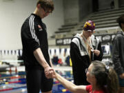 Tarik Kurta of Fort Vancouver shakes the hand of his coach Sarah Dunn on the podium after finishing second in the 50 freestyle at the 2A boys swimming state championship meet at the King County Aquatic Center in Federal Way on Saturday, Feb. 17, 2024.