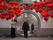 Residents take souvenir photos of a tree decorated with red lanterns Sunday ahead of the Chinese Lunar New Year at Ditan Park in Beijing.