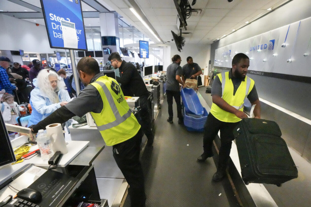 FILE - Passenger drop off their baggage at United Airlines in C Terminal at George Bush Intercontinental Airport, Thursday, Dec. 21, 2023, in Houston. United Airlines said Friday, Feb. 23, 2024, that it is raising its fees for checking bags, following a similar move earlier this week by American Airlines.