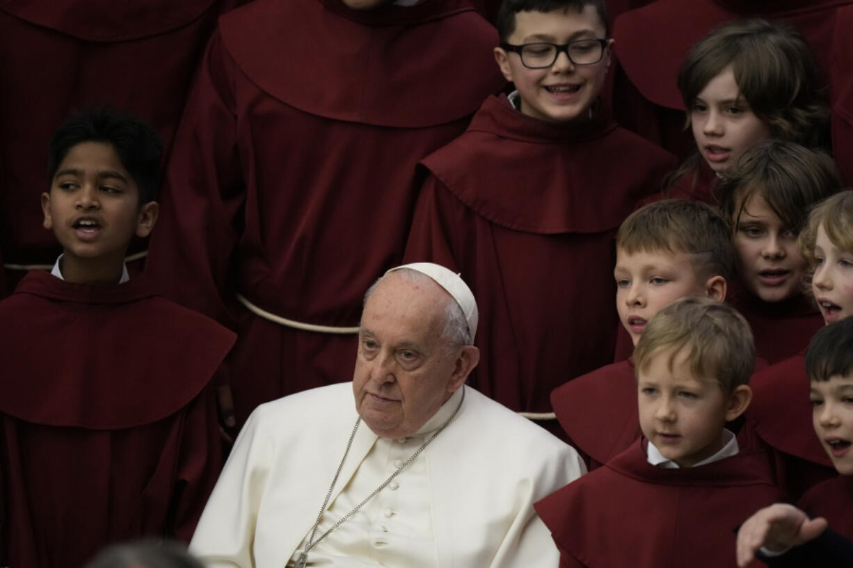 Pope Francis poses for photos with the young members of a chorus at the end of his weekly general audience in the Paul VI Hall, at the Vatican, Wednesday, Feb. 28, 2024.