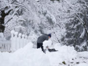 A person removes snow from a sidewalk during a winter storm in Doylestown, Pa., Tuesday, Feb. 13, 2024.