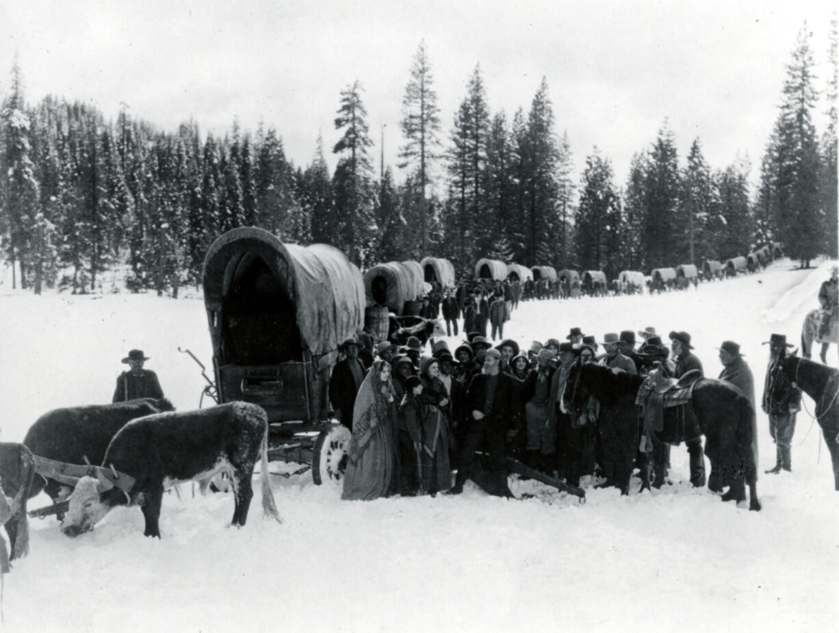 In this undated photo of an Oregon Trail reenactment, a long line of oxen-drawn wagons stops to rest along a trail. In 1878, a 21-year-old Missouri woman, Sarah Elizabeth Butler, kept a diary of her journey along the trail to Fort Vancouver.