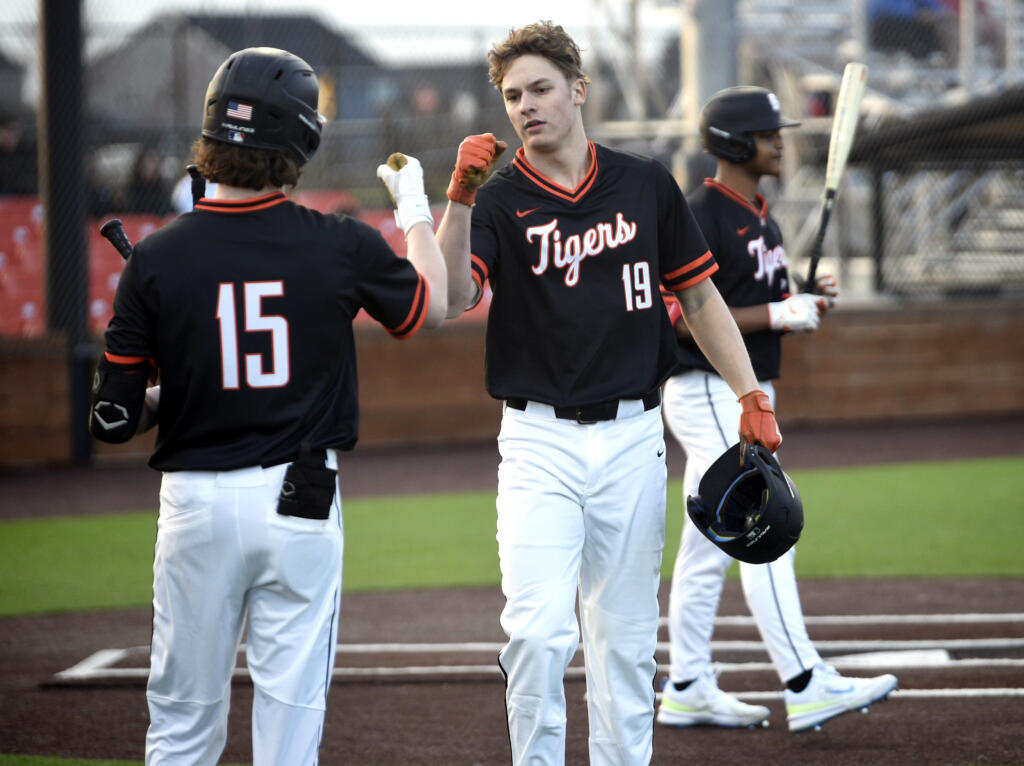 Battle Ground Jackson Hotchkiss (19) fist bumps teammate Keegan Moffatt (15) after Hotchkiss hit a solo home run during a season-opening, non-league baseball game against Ridgefield on Friday, March 8, 2024, at Ridgefield Outdoor Recreation Complex.