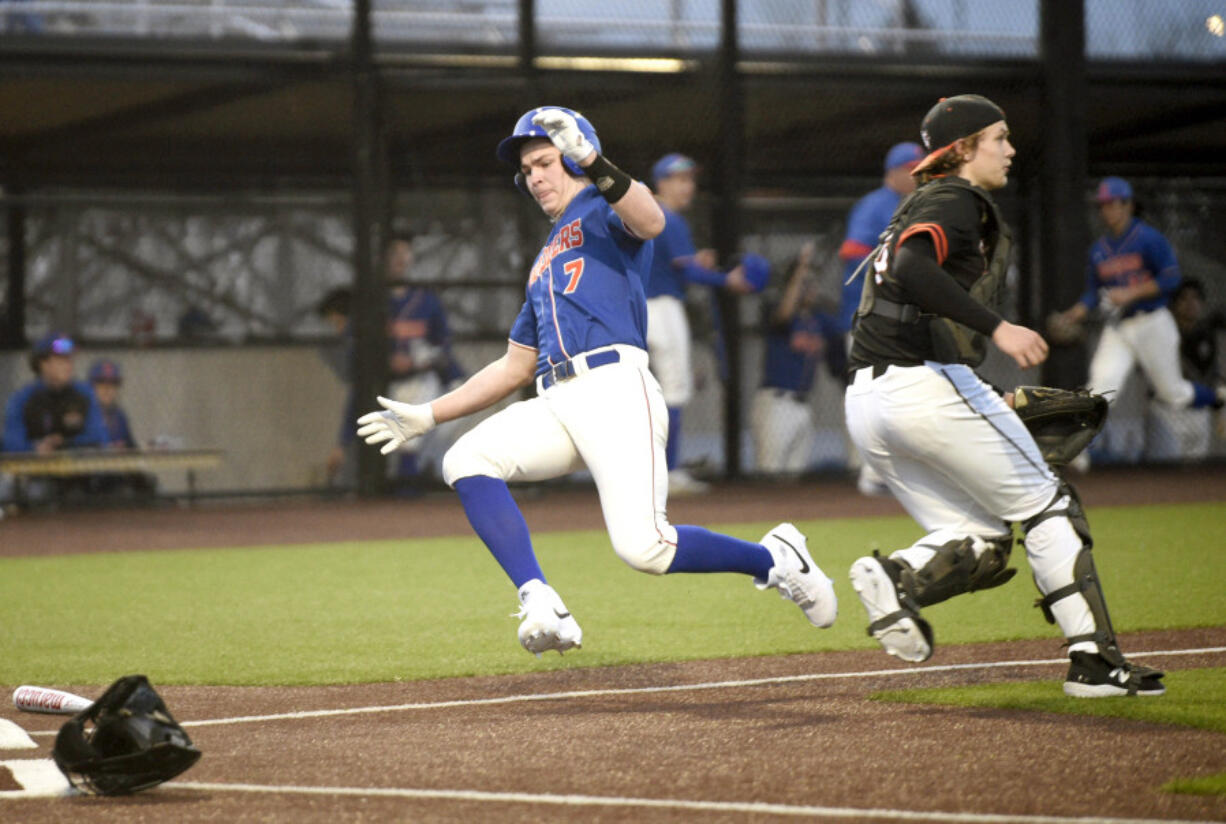 Ridgefield&#039;s Jared Gottsch (7) slides into home plate to score the Spudders&#039; first run of a season-opening, non-league baseball game against Battle Ground on Friday, March 8, 2024, at Ridgefield Outdoor Recreation Complex.