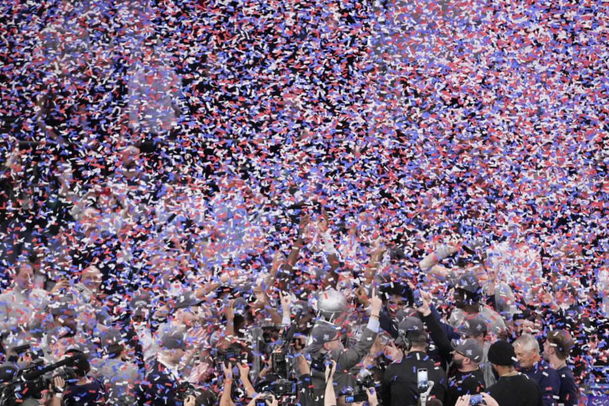 UConn head coach Dan Hurley, bottom center, holds up his arms as his team receives the Big East trophy after defeating Marquette in the championship game of the Big East Conference tournament Saturday. UConn is the top overall seed in the NCAA men&rsquo;s tournament.