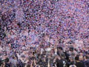 UConn head coach Dan Hurley, bottom center, holds up his arms as his team receives the Big East trophy after defeating Marquette in the championship game of the Big East Conference tournament Saturday. UConn is the top overall seed in the NCAA men&rsquo;s tournament.