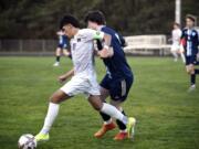 Columbia River's JP Guzman dribbles up the field while being tracked by Hockinson's Kirby VanderHouwen during a 2A GSHL boys soccer match on Tuesday, March 19, 2024, at Hockinson High School.