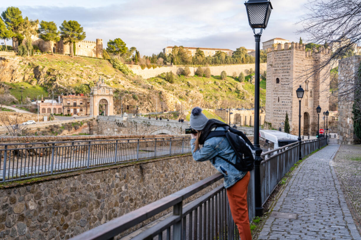 A solo traveler takes a photo of Castillo San Servando castle in Toledo, Spain.