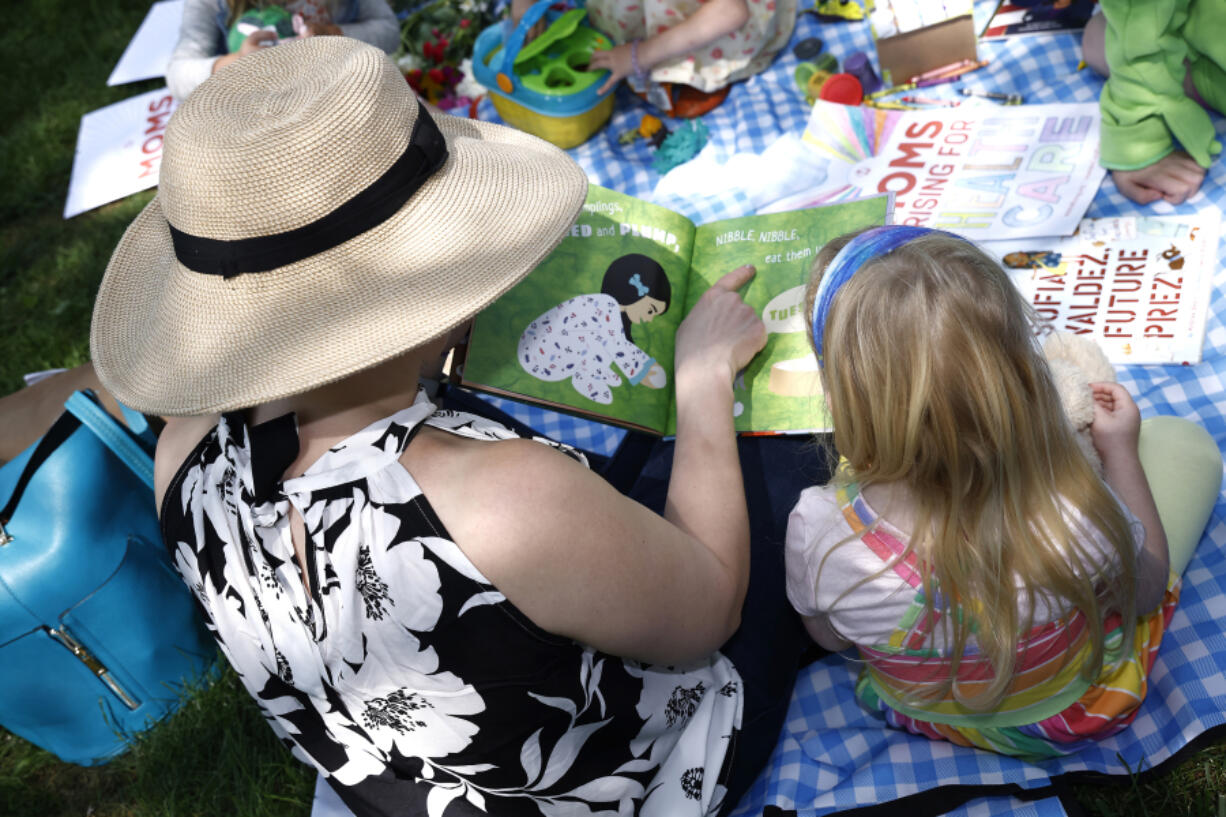 MomsRising members and their kids gather at a picnic on Capitol Hill to urge Congress to make child care affordable, pass paid leave, support care infrastructure, and raise the debt ceiling on May 17, 2023, in Washington, D.C. Women provide nearly 80% of household services that are crucial to sustaining spending and living standards, such as childcare and do-it-yourself home repairs.