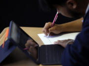 Audiel Miranda Cambron takes notes as he prepares for the digital SAT, Wednesday, March 6, 2024, at Holy Family Cristo Rey Catholic High School in Birmingham, Ala.