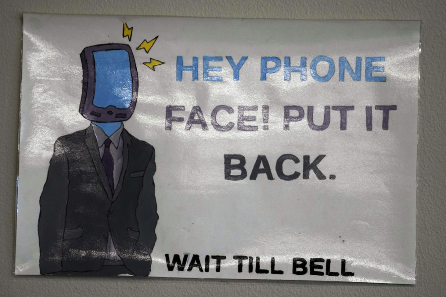 A sign is shown over a phone holder Feb. 23 in a classroom at Delta High School in Delta, Utah. At the rural Utah school, there is a strict policy requiring students to check their phones at the door when entering every class. Each classroom has a cellphone storage unit that looks like an over-the-door shoe bag with three dozen smartphone-sized slots.