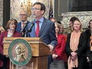 Washington state Attorney General Bob Ferguson (at podium) makes remarks prior to Gov. Jay Inslee (to the left of Ferguson) signing a package of gun legislation in April 2023. The legislation included a ban on the sale of firearms classified as assault weapons.