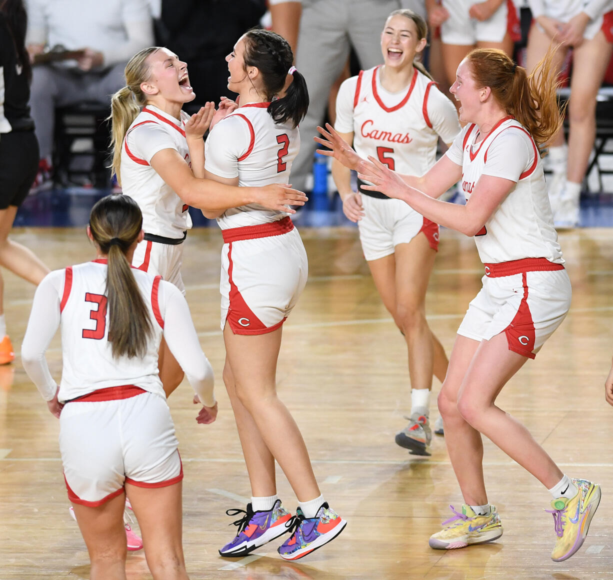 Camas players hug junior Kendall Mairs, center, after Mairs made a basket while being fouled Friday, March 1, 2024, during the Papermakers’ 60-48 win against Sumner in a WIAA 4A State Basketball semifinal game at the Tacoma Dome.