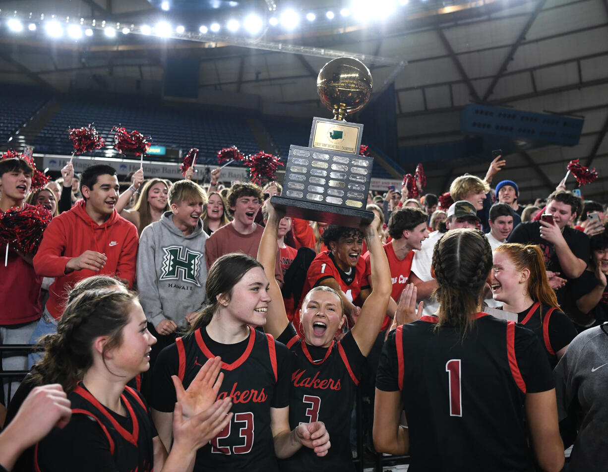 Camas senior Riley Sanz (3) lifts the state championship trophy in front of the Camas student section Saturday, March 2, 2024, after the Papermakers’ 57-41 win against Gonzaga Prep in the 4A WIAA State Basketball championship game at the Tacoma Dome.