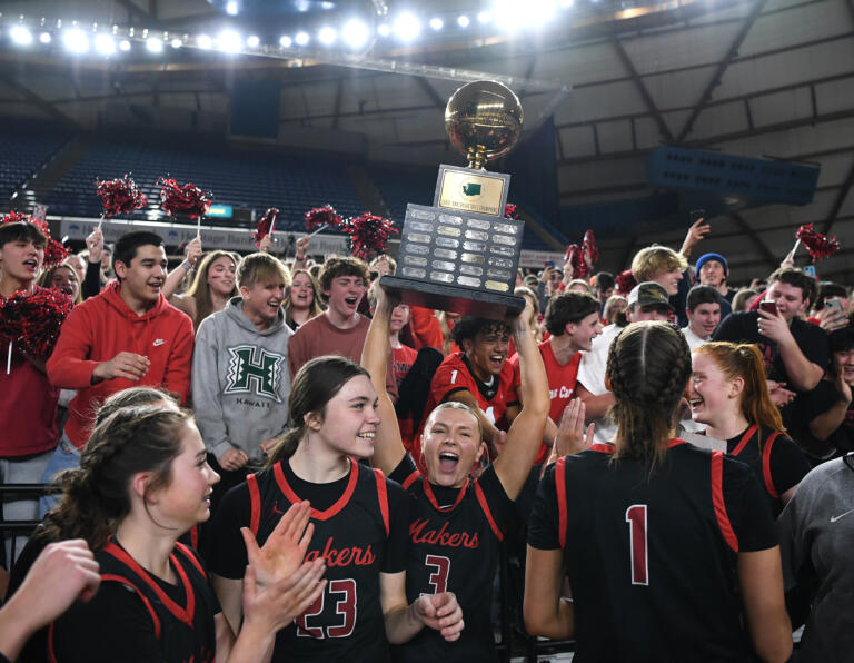 Camas senior Riley Sanz (3) lifts the state championship trophy in front of the Camas student section Saturday, March 2, 2024, after the Papermakers’ 57-41 win against Gonzaga Prep in the 4A WIAA State Basketball championship game at the Tacoma Dome.