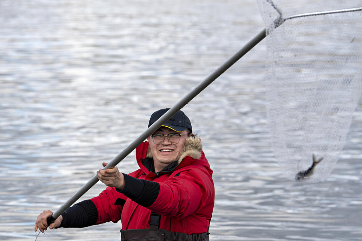 Jia Liu of Auburn is all smiles as he snags a smelt along the Cowlitz River on Tuesday afternoon.