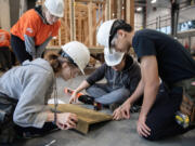 Evergreen High School sophomore Rue Rollins, 16, from left, helps build a ramp Thursday morning under the helpful eye on Trillium Allison of The Home Depot while joined by classmates Domonick Good, 15, and Juan Abundiz Piz, 14. The volunteers helped students with their building skills in hopes of encouraging them to pursue trade careers.