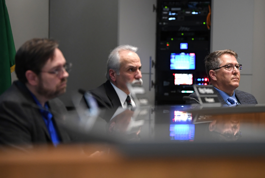 Evergreen Public Schools board of directors president Rob Perkins, from left, member Gary Wilson and Superintendent John Boyd listen to public comment Tuesday evening at an Evergreen Public Schools board of directors meeting at district headquarters in Vancouver. The board voted to approve $18.7 million budget cuts to the district next year.