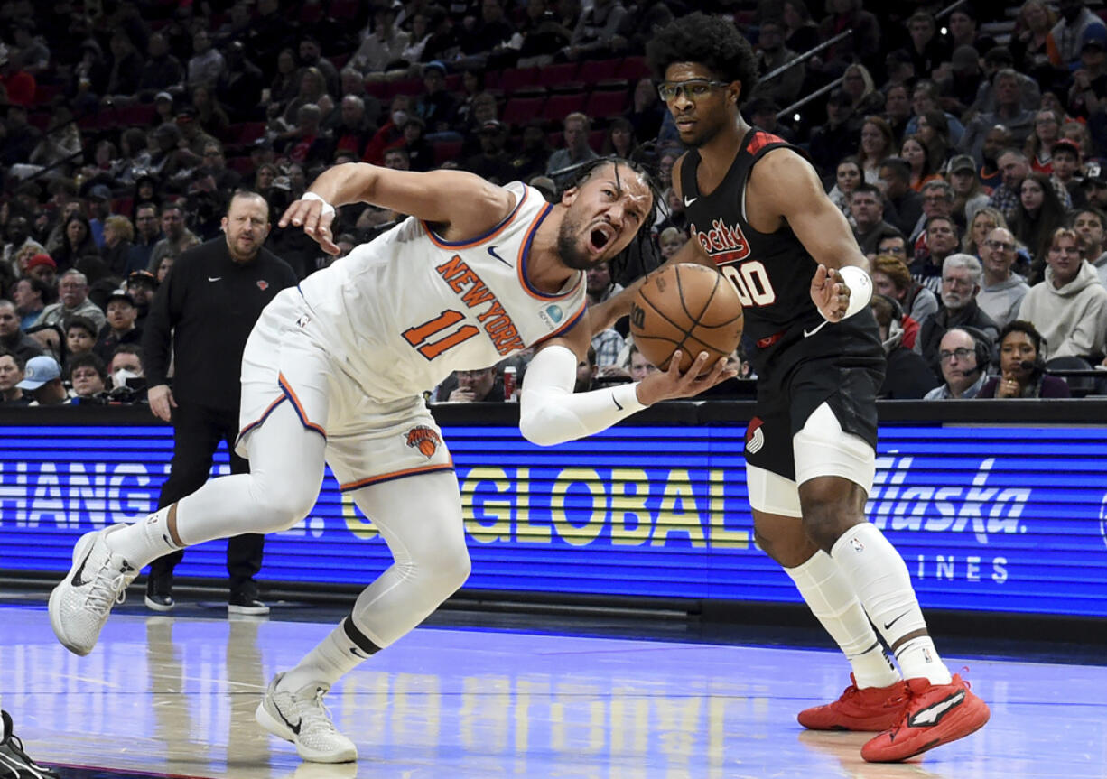 New York Knicks guard Jalen Brunson, left, drives to the basket against Portland Trail Blazers guard Scoot Henderson, right, during the first half of an NBA basketball game in Portland, Ore., Thursday, March 14, 2024.