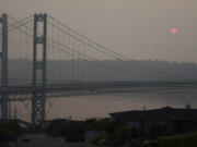 FILE - The sun sets through smoky air behind the Narrows Bridge in Tacoma, Wash., on Aug. 19, 2018. A coroner's investigation into the death of a man in Los Angeles in February 2024 revealed that he was a suspect in a 2008 Washington state child rape who was believed to have jumped to his death from a bridge on Puget Sound years ago, authorities said. A witness reported seeing the man jump from the Tacoma Narrows Bridge on March 29, 2009. (AP Photo/Ted S.