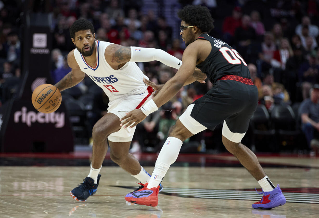 Los Angeles Clippers forward Paul George, left, dribbles the ball around Portland Trail Blazers guard Scoot Henderson during the second half of an NBA basketball game in Portland, Ore., Wednesday, March 20, 2024.