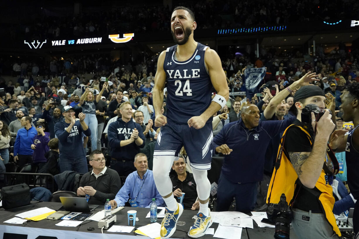 Yale guard Yassine Gharram (24) stands on a table after celebrating with fans after Yale upset Auburn in a first-round college basketball game in the NCAA Tournament in Spokane, Wash., Friday, March 22, 2024. (AP Photo/Ted S.