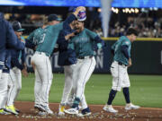 Seattle Mariners' Ty France empties a tub of bubble gum onto the head of the Julio Rodriguez, second from fight, after the team's win in a baseball game against the Boston Red Sox, Saturday, March 30, 2024, in Seattle.