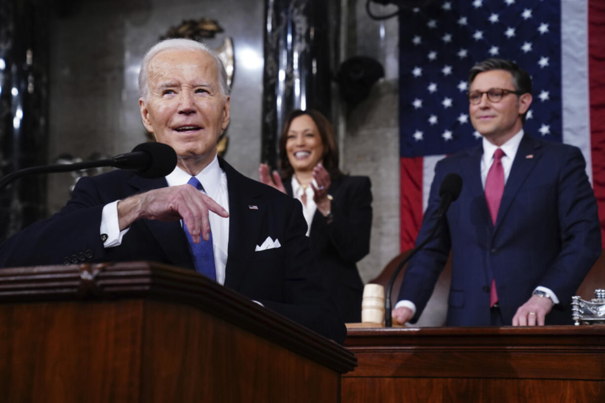 President Joe Biden delivers the State of the Union address to a joint session of Congress at the Capitol, Thursday, March 7, 2024, in Washington. Standing are Vice President Kamala Harris, background center, and House Speaker Mike Johnson, R-La., background right.