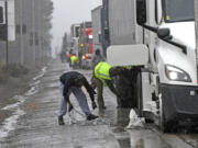 A long line of trucks are parked off the west bound I-80 as drivers put chains on the truck wheels in preparation for the snow storm over the Sierra Nevada on Thursday, Feb. 29, 2024, in Lake Tahoe, Calif.