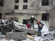 FILE - People walk with belongings out from an apartment building destroyed after Tuesday&rsquo;s Russian attack in Kyiv, Ukraine, Jan. 3, 2024. House Democrats on Tuesday, March 12, 2024, launched a long-shot effort to push $95 billion in aid for Ukraine, Israel and Taiwan to a vote. The move ramps up pressure on House Speaker Mike Johnson to take up the foreign funding package.