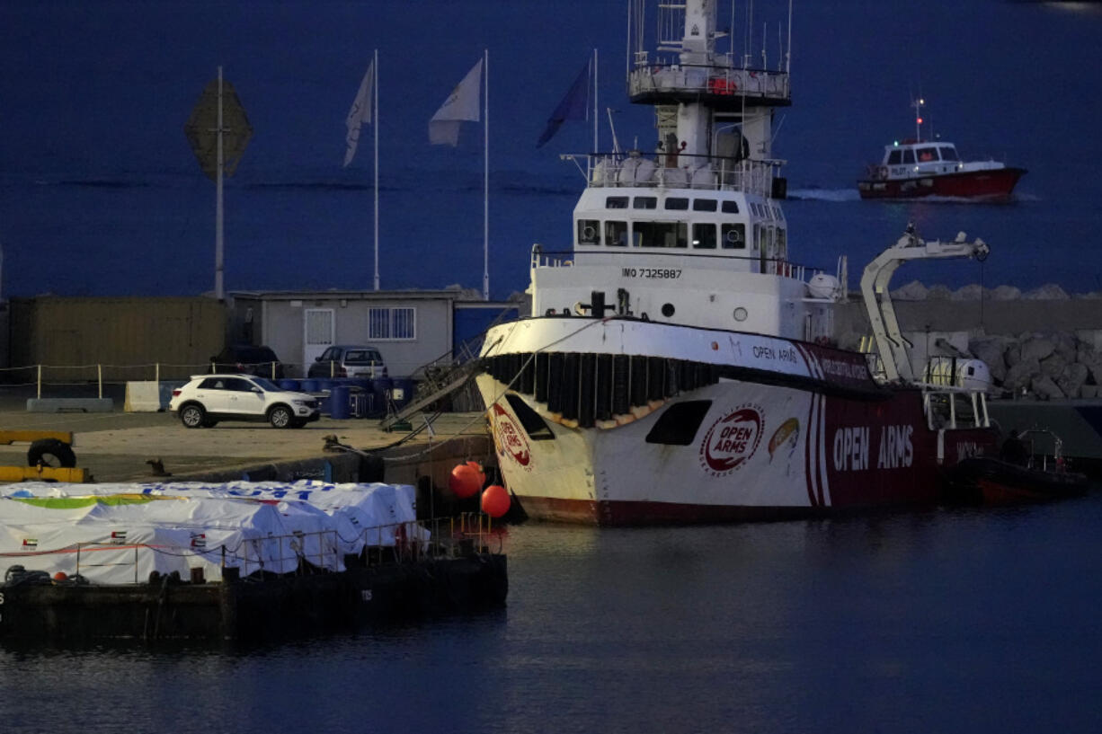 Aid packages are seen left, on a platform near to the docked ship belonging to the Open Arms aid group, as it prepares to ferry some 200 tonnes of rice and flour directly to Gaza, at the port in Larnaca, Cyprus, Sunday, March 10, 2024. The European Commission president said Friday the Open Arms ship will make a pilot voyage as international donors launched a sea corridor to supply the besieged territory that is facing widespread hunger after five months of war.