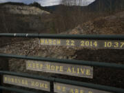 The Oso landslide scar is seen near a sign at the memorial site on Saturday, Feb. 17, 2024, in Oso, Wash. The mountainside collapsed, obliterating a neighborhood and 43 lives in the worst landslide disaster in U.S. history.