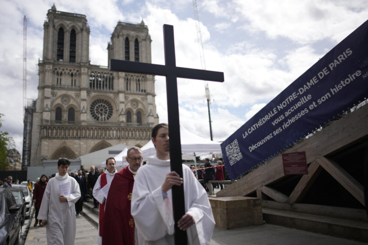 A priest holds a cross during a Good Friday ceremony outside Notre Dame cathedral , as part of Easter celebrations, Friday, March 29, 2024 in Paris.