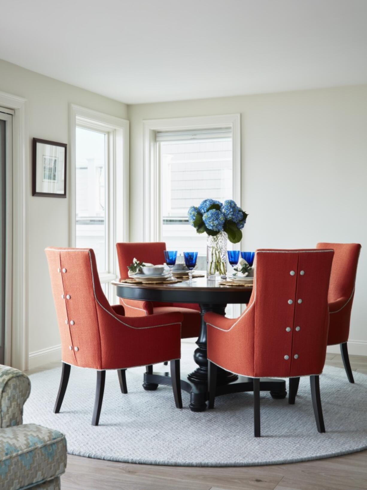 &ldquo;The orange dining chairs in this airy waterfront dining room are from Kravet,&rdquo; says Designer Jillian Hayward Schaible of Susan Hayward interiors. She says you can spend less on small furnishings and accessories, but it&rsquo;s worth investing in the pieces that you sit, sleep and eat on.