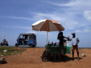 FILE - A man buys a cool drink from a roadside vendor on a sunny day in Mahawewa, a village north of Colombo, Sri Lanka, Feb. 29, 2024. Earth has exceeded global heat records in February, according to the European Union climate agency Copernicus.