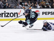 Seattle Kraken left wing Andre Burakovsky (95) goes down with Winnipeg Jets center Mark Scheifele (55) called for tripping during the third period of an NHL hockey game, Friday, March 8, 2024, in Seattle. The Jets won 3-0.