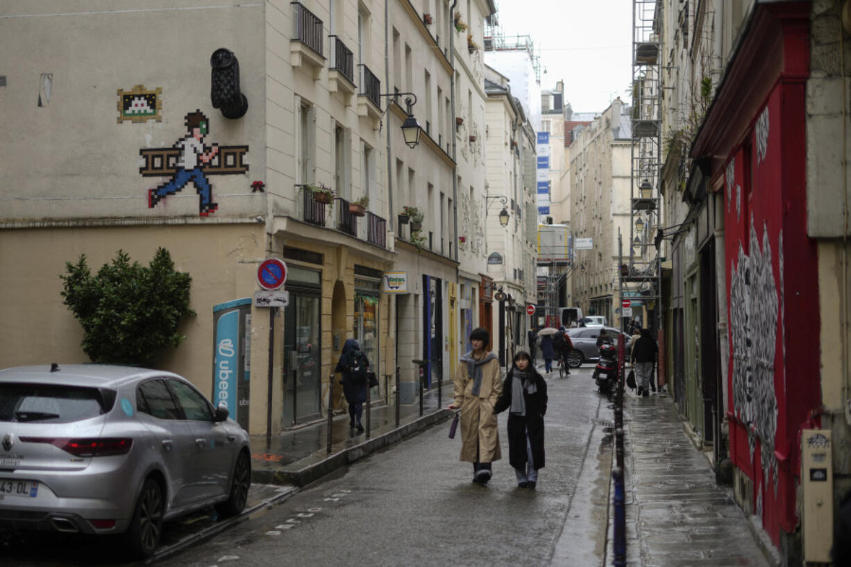 A mosaic by French artist Invader, top left, decorates a Paris street.