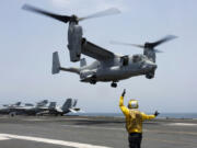 FILE -In this image provided by the U.S. Navy, Aviation Boatswain&rsquo;s Mate 2nd Class Nicholas Hawkins, signals an MV-22 Osprey to land on the flight deck of the USS Abraham Lincoln in the Arabian Sea on May 17, 2019. The military has greenlighted its Osprey to return to flight, three months after a part failure led to the deaths of eight service members in a crash in Japan in November. Naval Air Systems Command announced it on Friday.  (Mass Communication Specialist 3rd Class Amber Smalley/U.S.